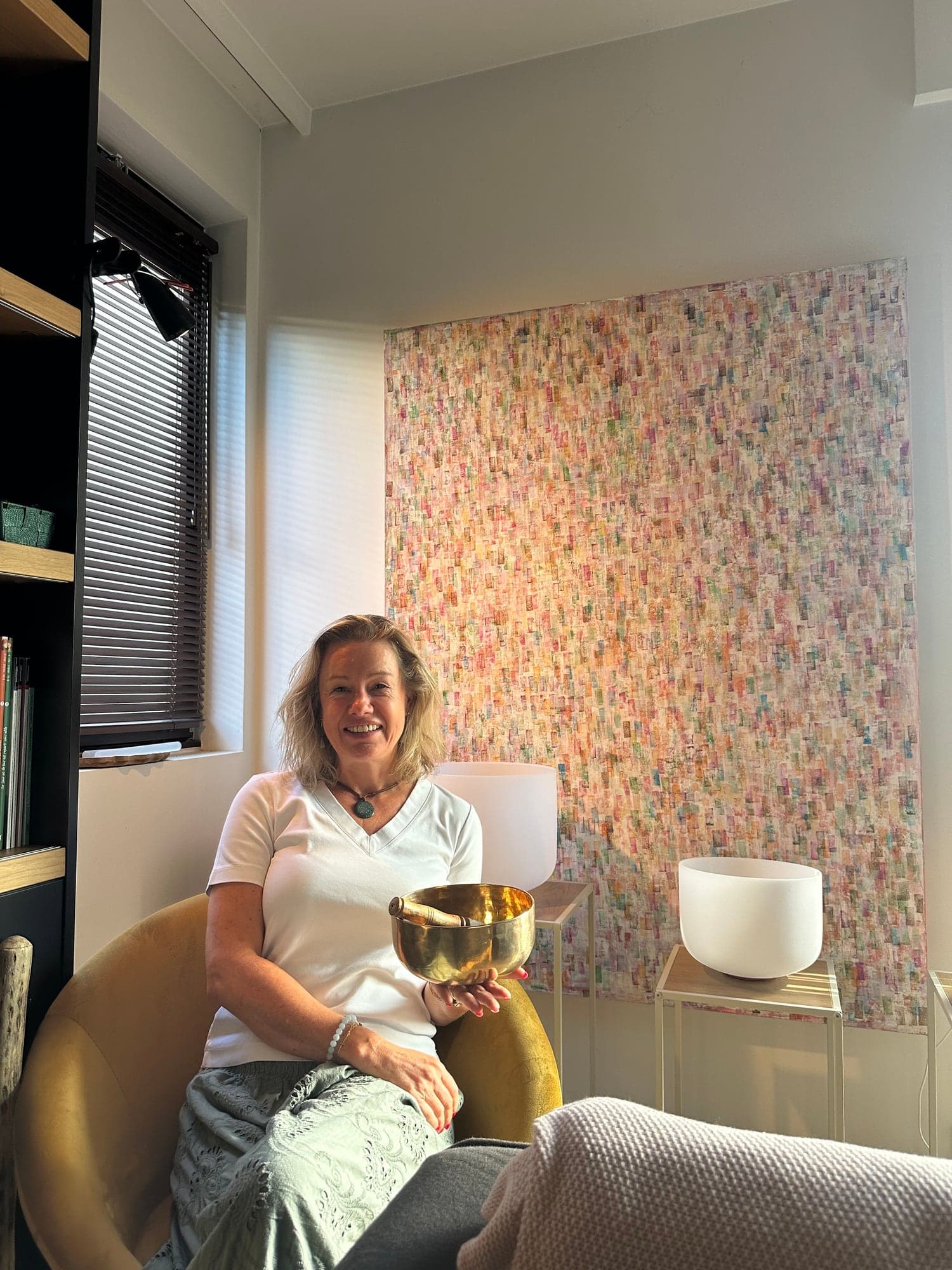 Catherine, assise dans un fauteuil, tient un bol tibétain entre ses mains