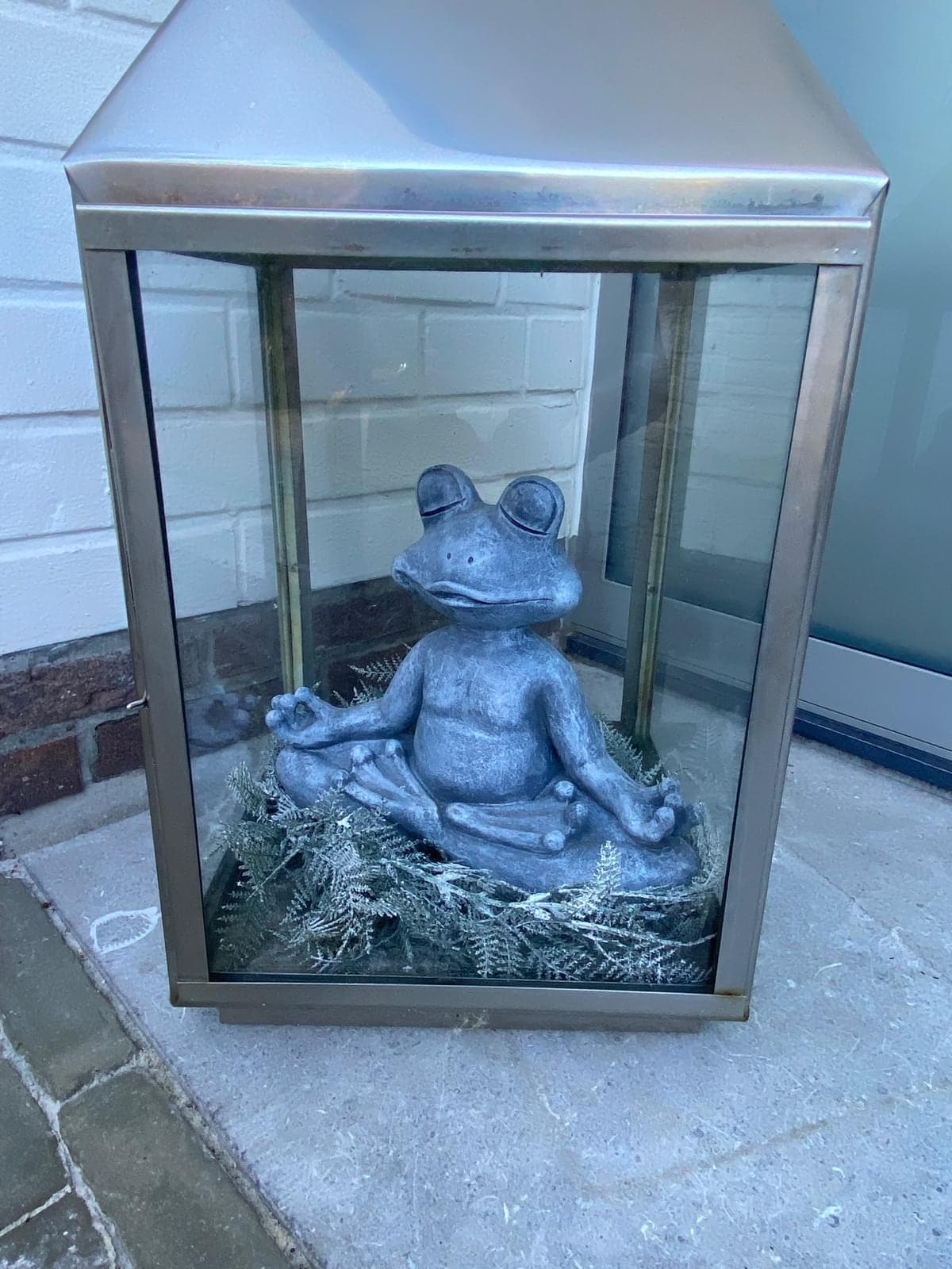 Une petite grenouille en méditation, posée dans une lanterne à l’entrée