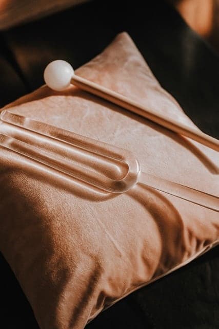 Un diapason en cristal et son maillet posés sur un coussin